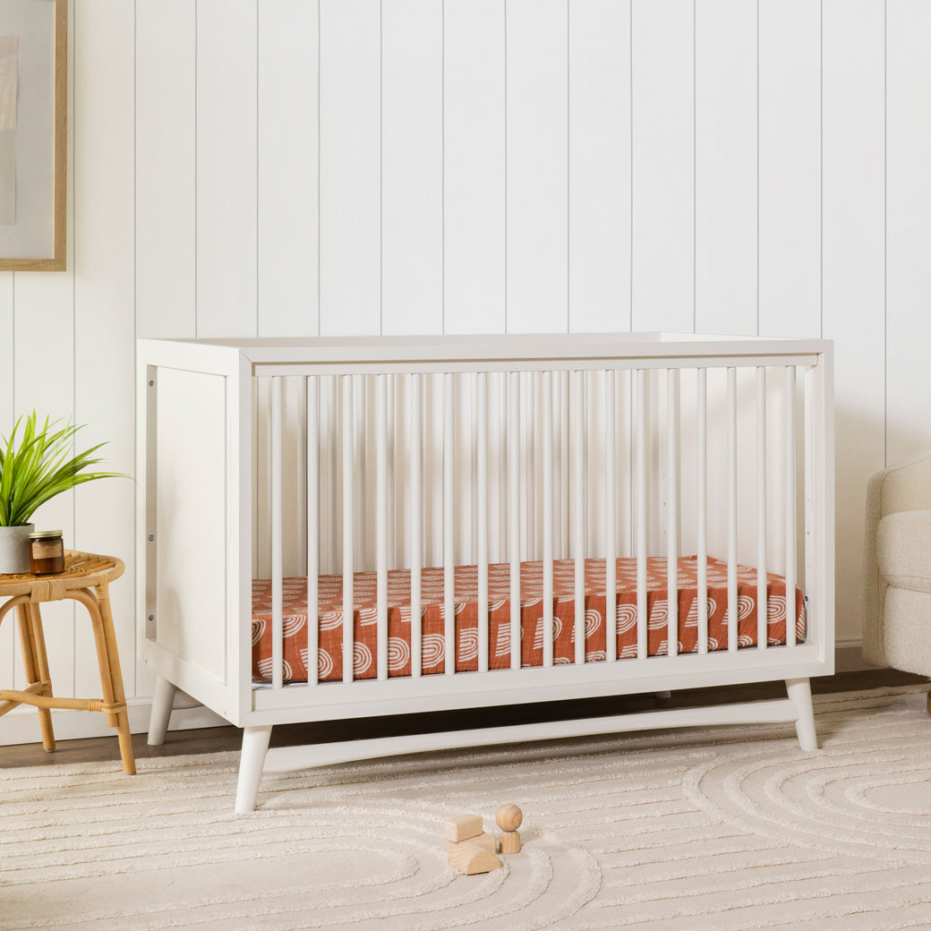 Babyletto's Peggy 3-in-1 Convertible Crib next to a table with plant  in -- Color_Warm White