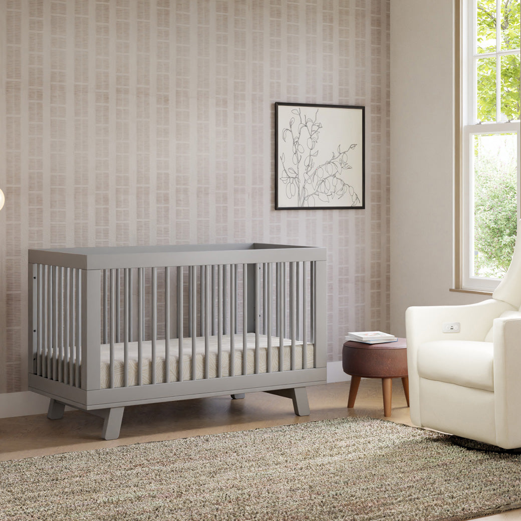 Babyletto Hudson 3-in-1 Crib next to a recliner and window  in -- Color_Grey