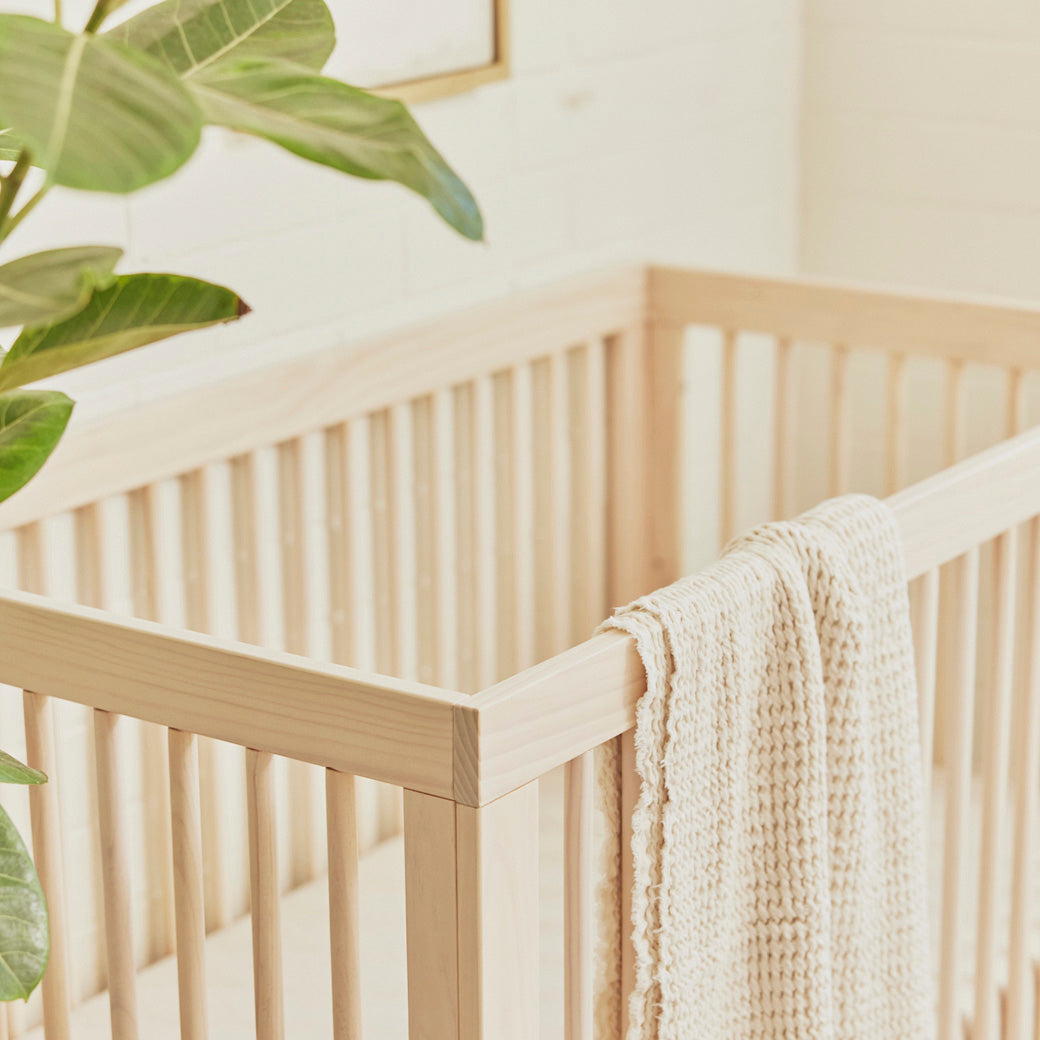 Closeup of The Babyletto Hudson 3-in-1 Crib with blanket on rail  in -- Color_Washed Natural