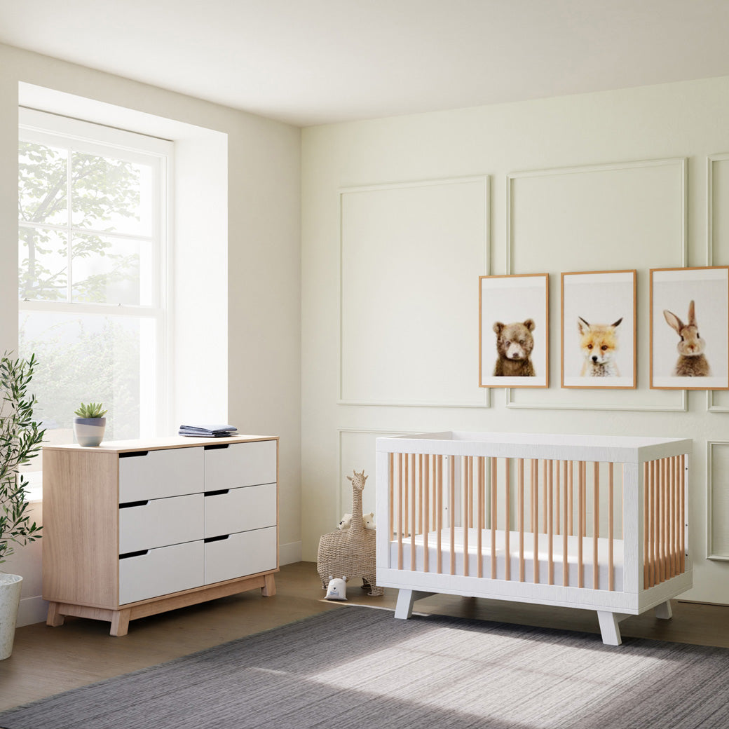 Babyletto Hudson 3-in-1 Crib next to a dresser and giraffe basket  in -- Color_Washed Natural/White