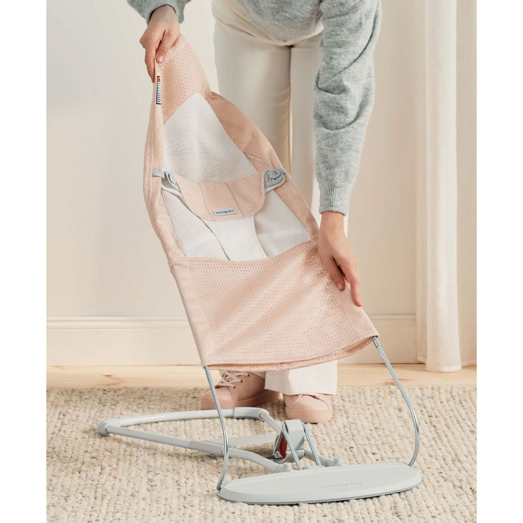Mom taking off fabric from the BABYBJÖRN Bouncer Balance Soft in -- Color_Pearly Pink/White Mesh