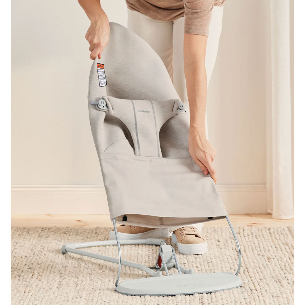 Mom taking off the fabric of the BABYBJÖRN Bouncer Bliss in -- Color_Light Beige 3D Jersey