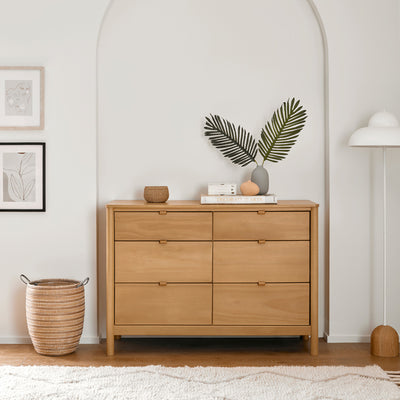 Babyletto Bondi 6-Drawer Dresser next to a basket and a lamp  in -- Color_Honey