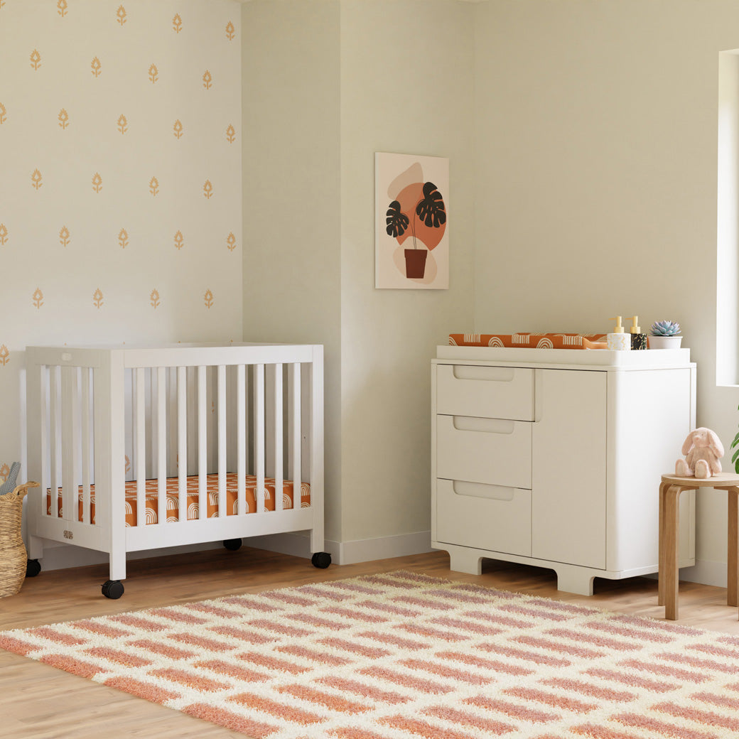 Babyletto Yuzu 3-Drawer Changer Dresser next to a crib and stool  in -- Color_White