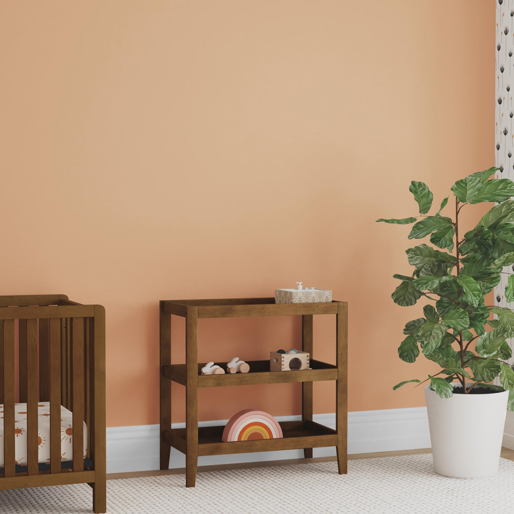 Carter's by DaVinci Colby Changing Table next to a crib and plant  in -- Color_Walnut