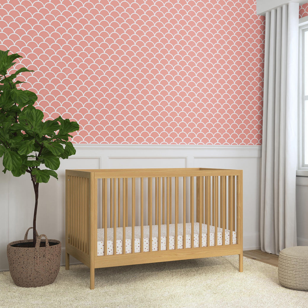 DaVinci Birdie 3-in-1 Convertible Crib next to a plant and window in -- Color_Honey