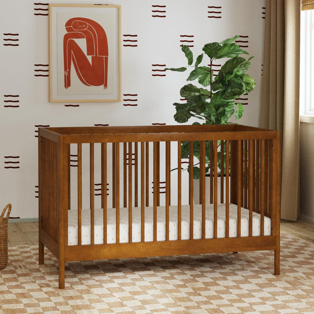 DaVinci Birdie 3-in-1 Convertible Crib next to a plant and window  in -- Color_Walnut