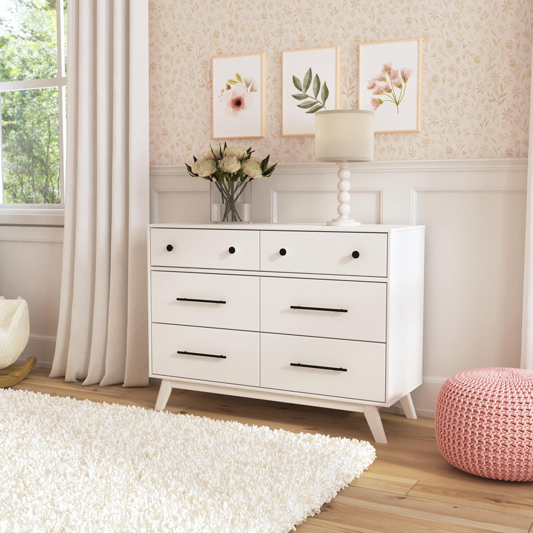 Angled view of DaVinci Otto 6-Drawer Dresser with flowers and a lamp on top in -- Color_White