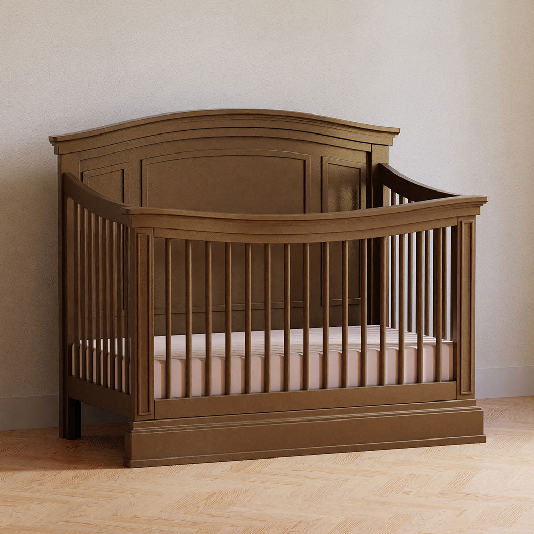 Namesake's Durham 4-in-1 Convertible Crib next to a wall in a room  in -- Color_Derby Brown
