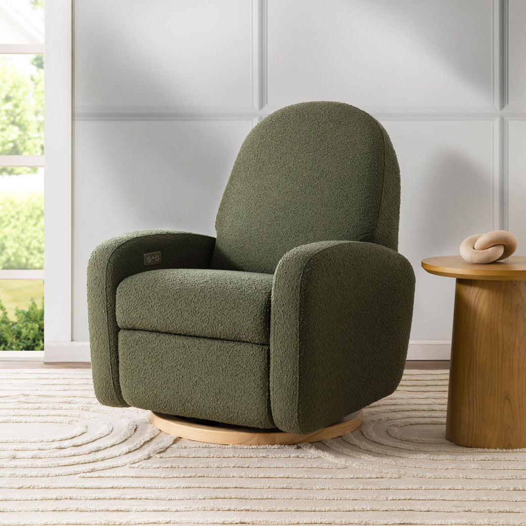 The Babyletto Nami Glider Recliner next to a coffee table in -- Color_Olive Boucle with Light Wood Base