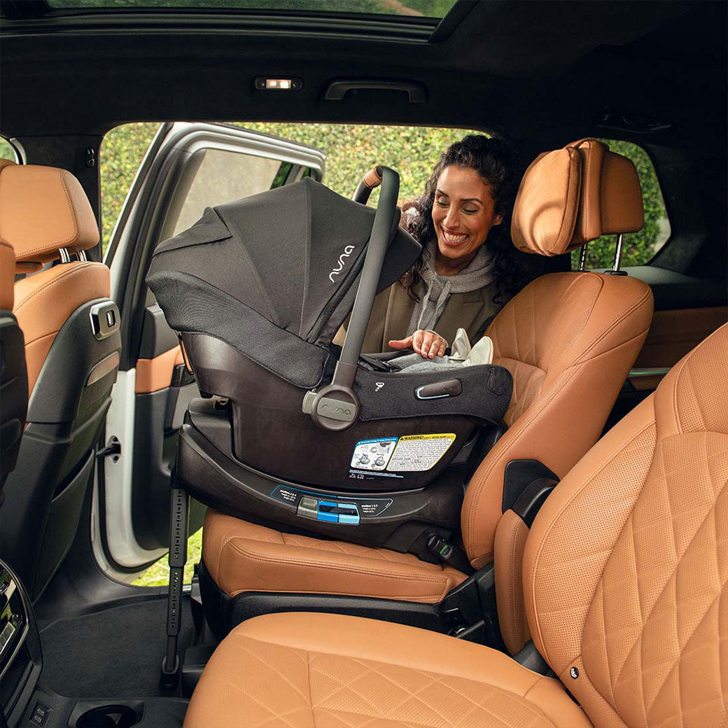 Mom putting the Nuna PIPA Aire RX Infant Car Seat in the car + PIPA RELX Base in -- Lifestyle