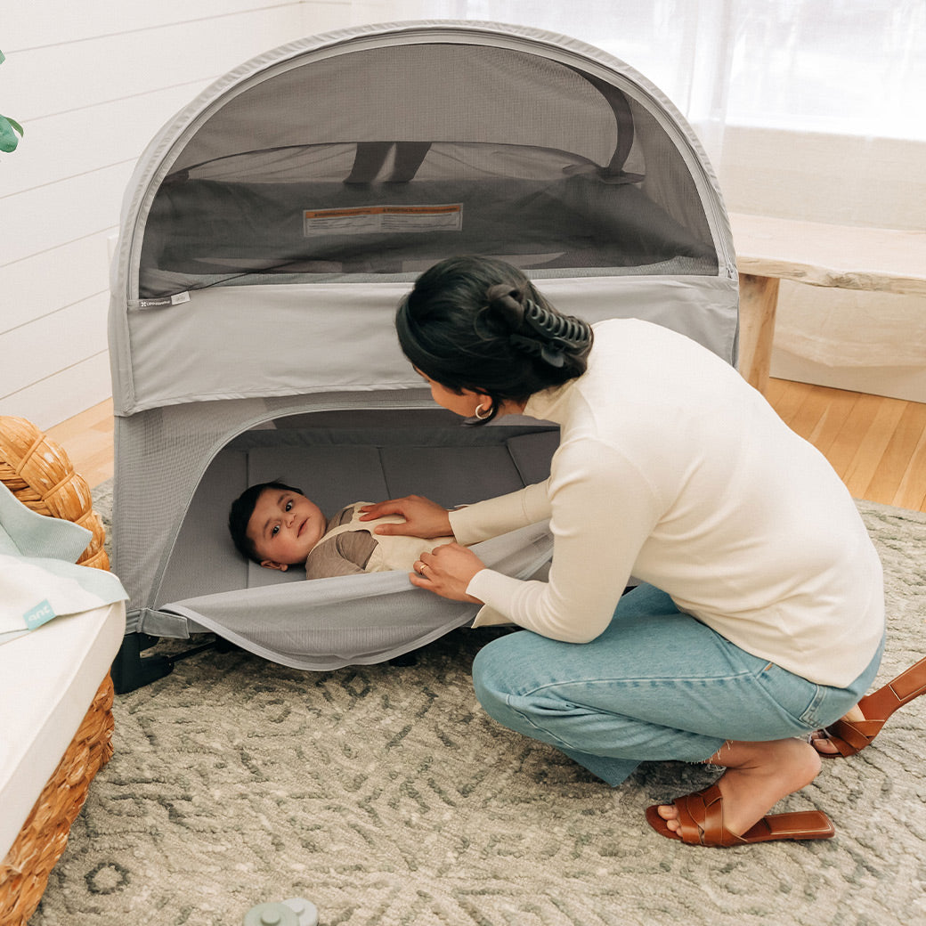 mother tucking in child through easy access zipper on remi travel crib -- Lifestyle