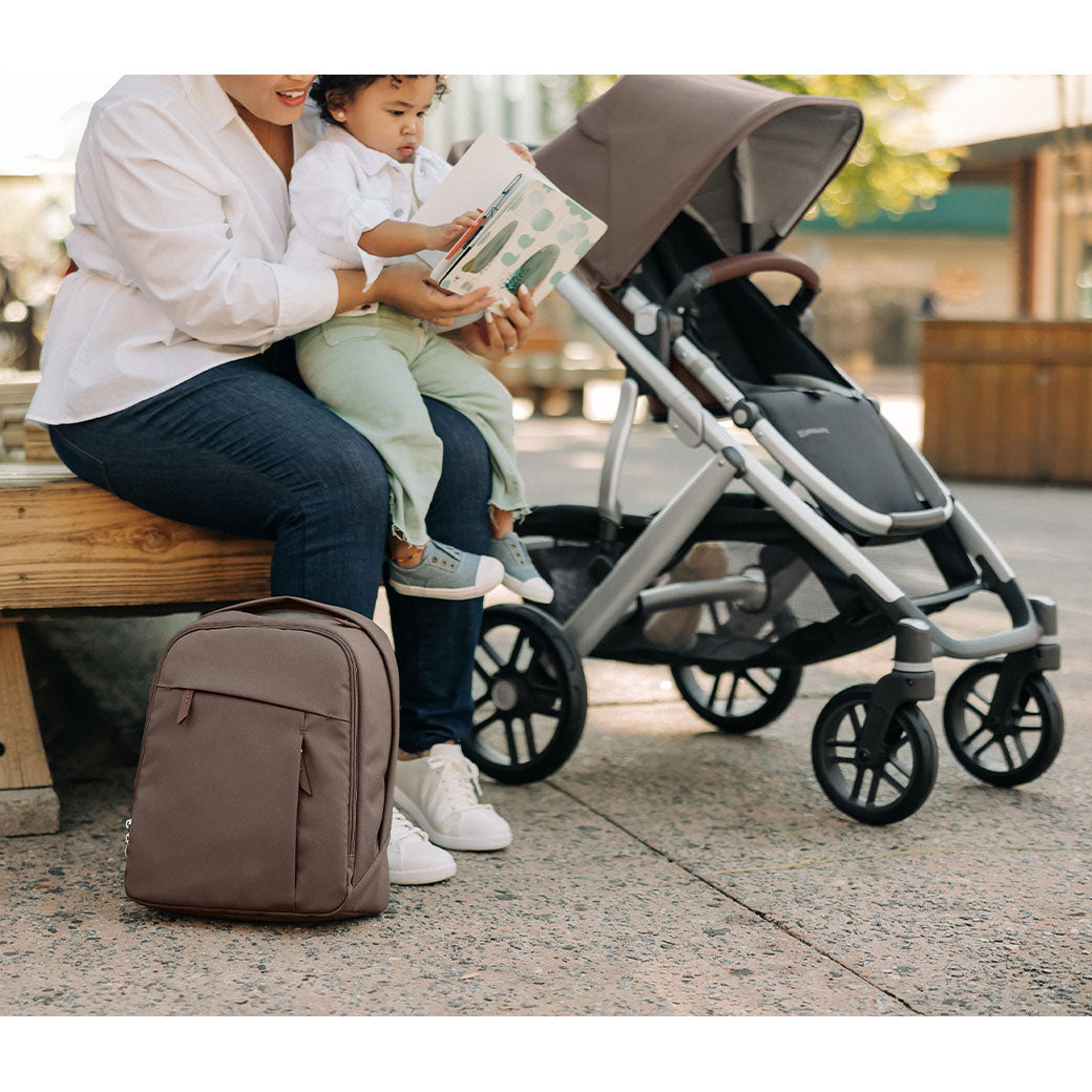 A mommy sitting on a bench with a toddler next to the Uppababy Vista V2 in -- Color_Theo