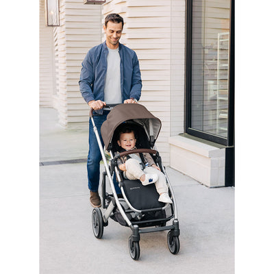 Dad pushing baby in UPPAbaby CRUZ V2 Travel System stroller in -- Color_Theo
