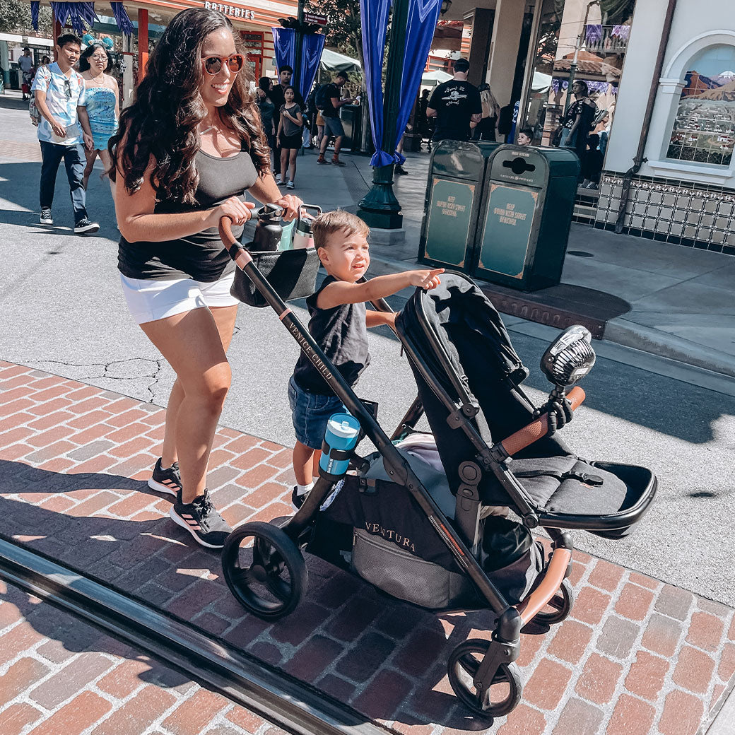 Mom and toddler walking with the Venice Child Ventura Single to Double Sit-and-Stand Stroller & 2nd Toddler Seat in -- Lifestyle
