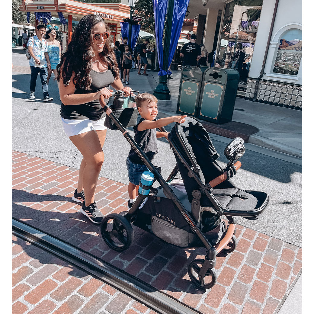 Mom pushing a toddler on the Venice Child Ventura Single to Double Sit-and-Stand Stroller & Bassinet in -- Lifestyle