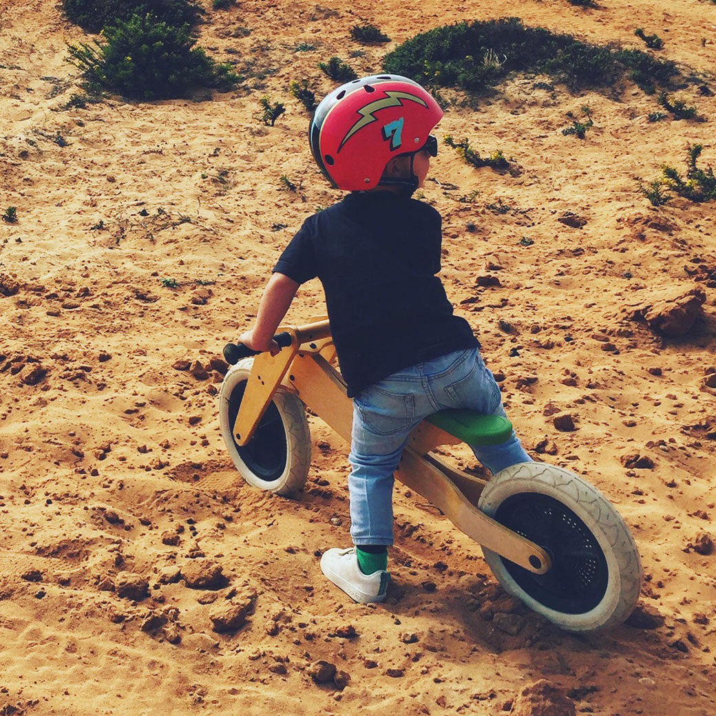 Toddler riding the Wishbone 2-in-1 Bike on sand in -- Color_Natural