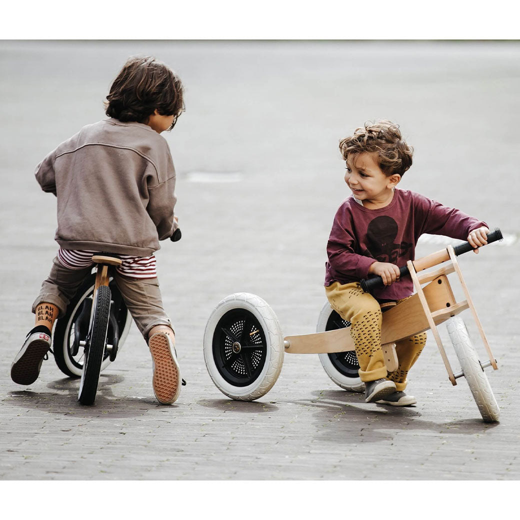 Two toddlers  on bikes, the younger one on the Wishbone 3-in-1 Bike in -- Color_Natural
