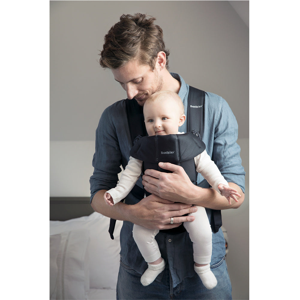 Dad holding smiling baby in the BABYBJÖRN Baby Carrier Mini in -- Color_Black Woven