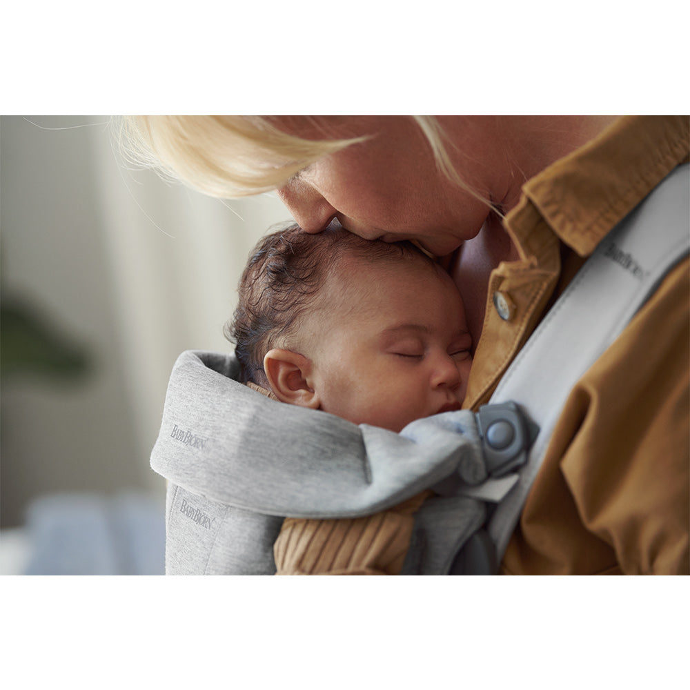 Mom kissing sleeping baby in BABYBJÖRN Baby Carrier Mini in -- Color_Light Gray 3D Jersey