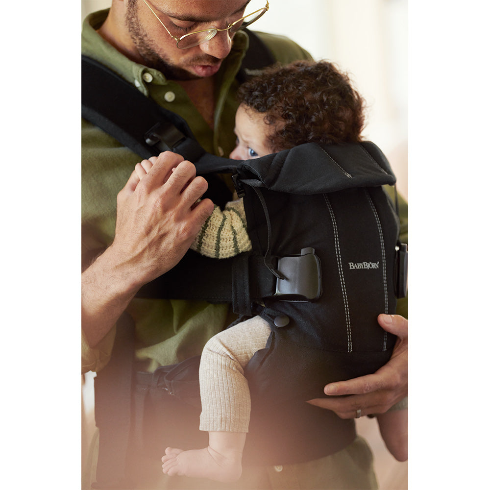 Dad holding baby in BABYBJÖRN Baby Carrier One in -- Color_Black Woven Mix