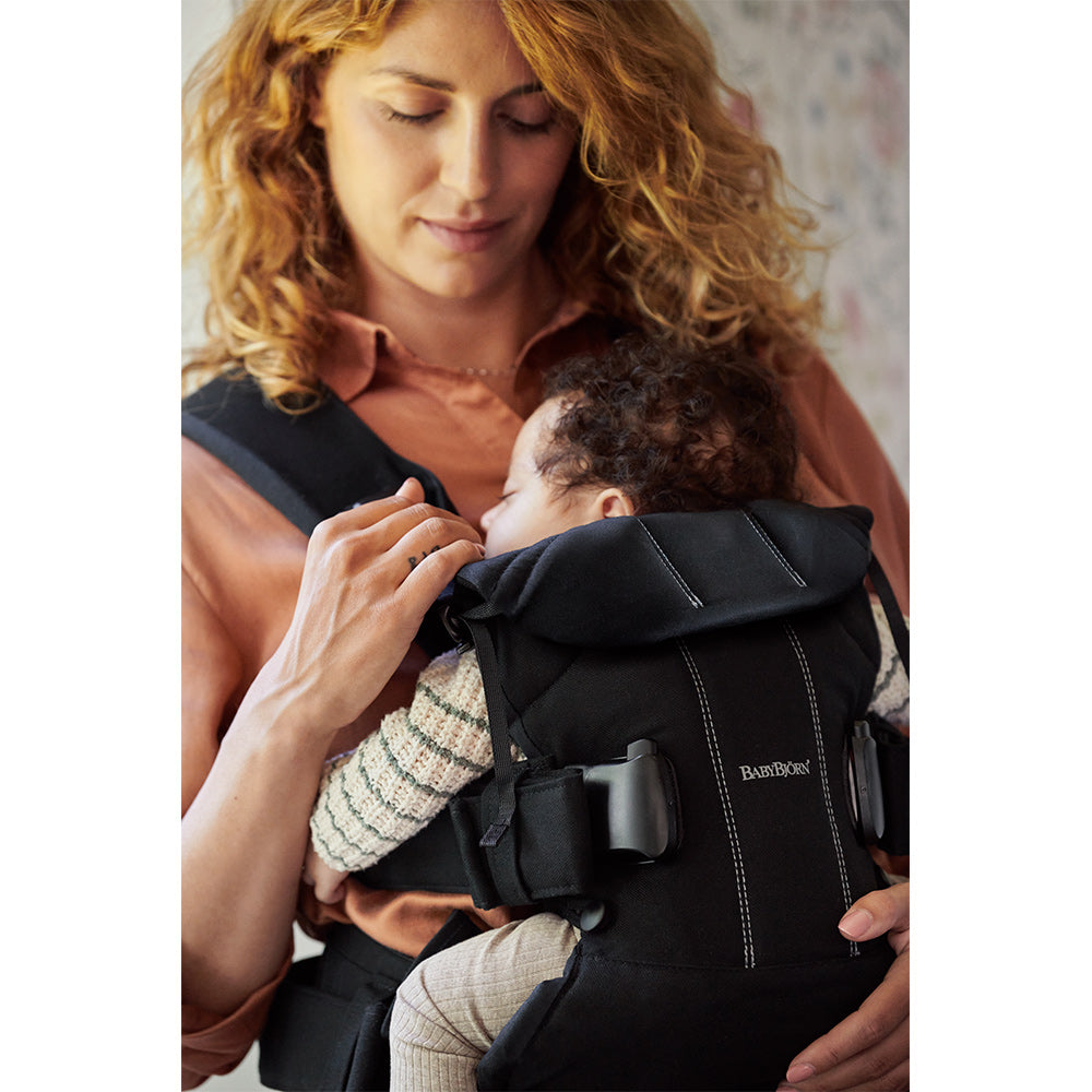 Mom looking down at the baby in BABYBJÖRN Baby Carrier One in -- Color_Black Woven Mix