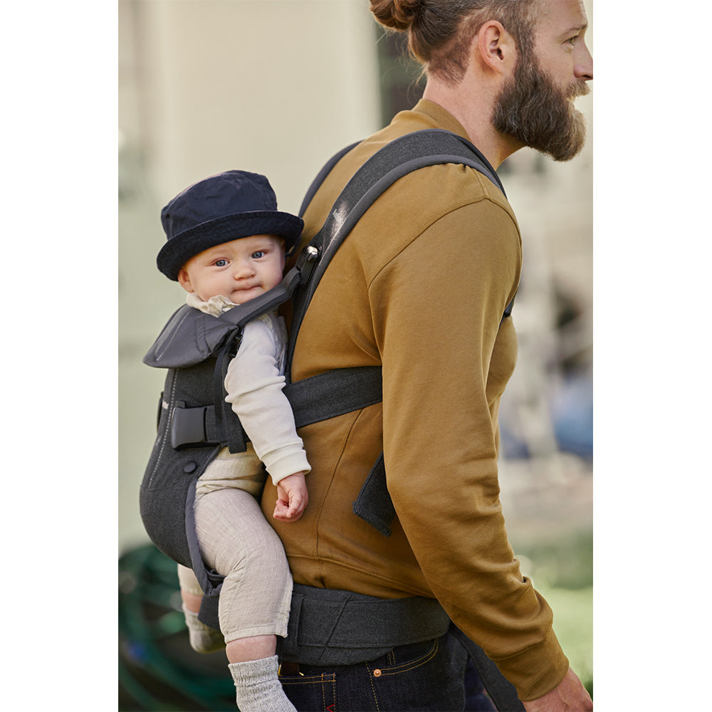 Side view of baby in dads back in the BABYBJÖRN Baby Carrier One in -- Color_Denim Gray/Dark Gray Woven Mix