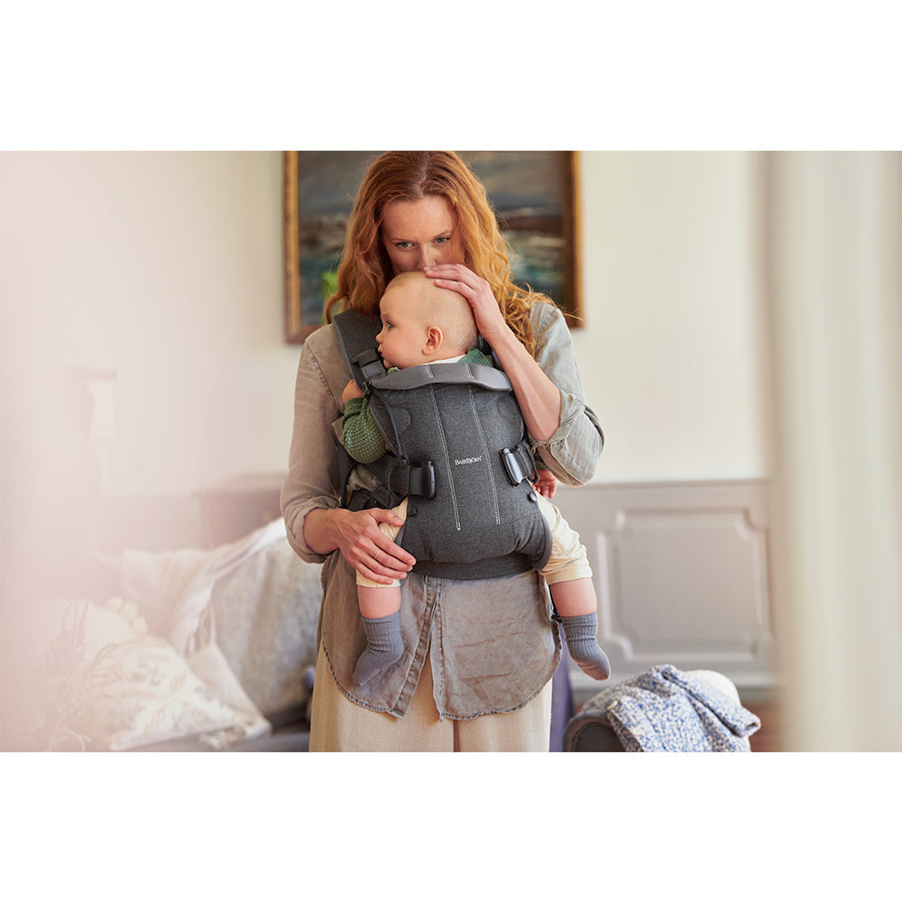 Mother kissing baby in forehead while in BABYBJÖRN Baby Carrier One in -- Color_Denim Gray/Dark Gray Woven Mix