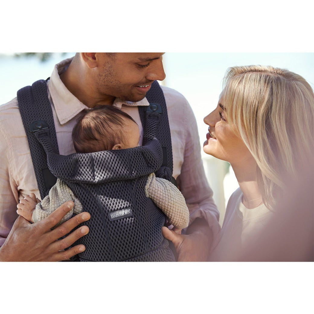 Mom and Dad smiling at each other while baby is sleeping in the BABYBJÖRN Baby Carrier Free in -- Color_Anthracite 3D Mesh