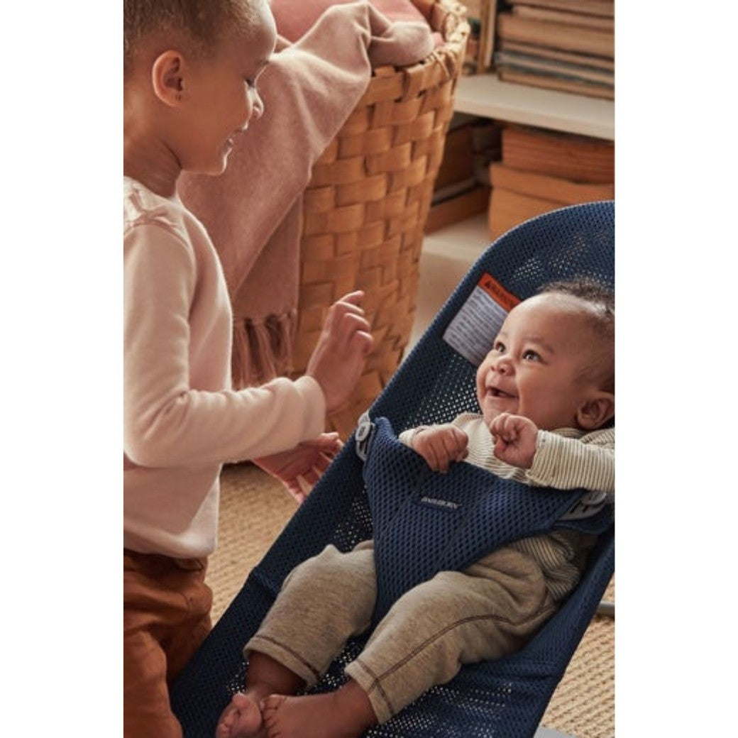 Baby laughing at toddler sister in BABYBJÖRN Bouncer Bliss in -- Color_Navy Blue Mesh