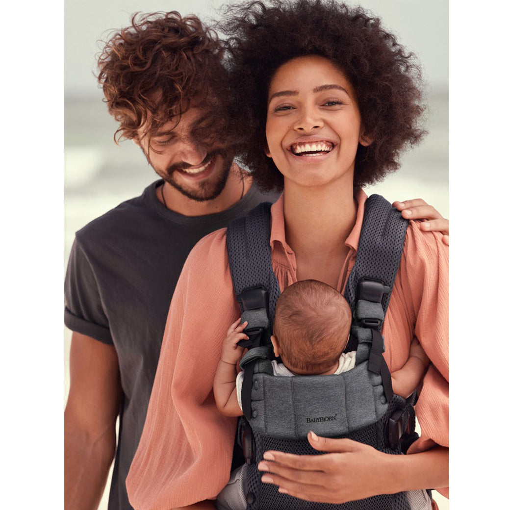 Mom carrying Babybjorn Baby Carrier Harmony with dad next to them in -- Color_Anthracite