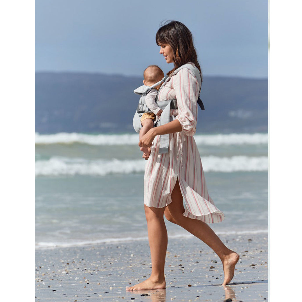 Mom walking baby on the beach with the BABYBJÖRN Baby Carrier One in -- Color_Silver 3D Mesh Air
