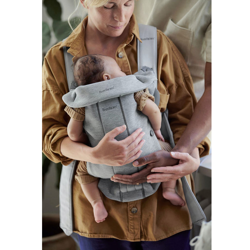 Mom carrying baby in BABYBJÖRN Baby Carrier Mini and holding dad's hand in -- Color_Light Gray 3D Jersey