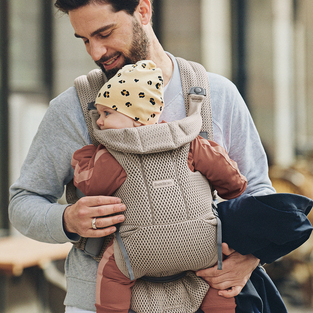 Dad holding baby with yellow hat in Babybjorn Baby Carrier Free in -- Color_Beige Grey 3D Mesh