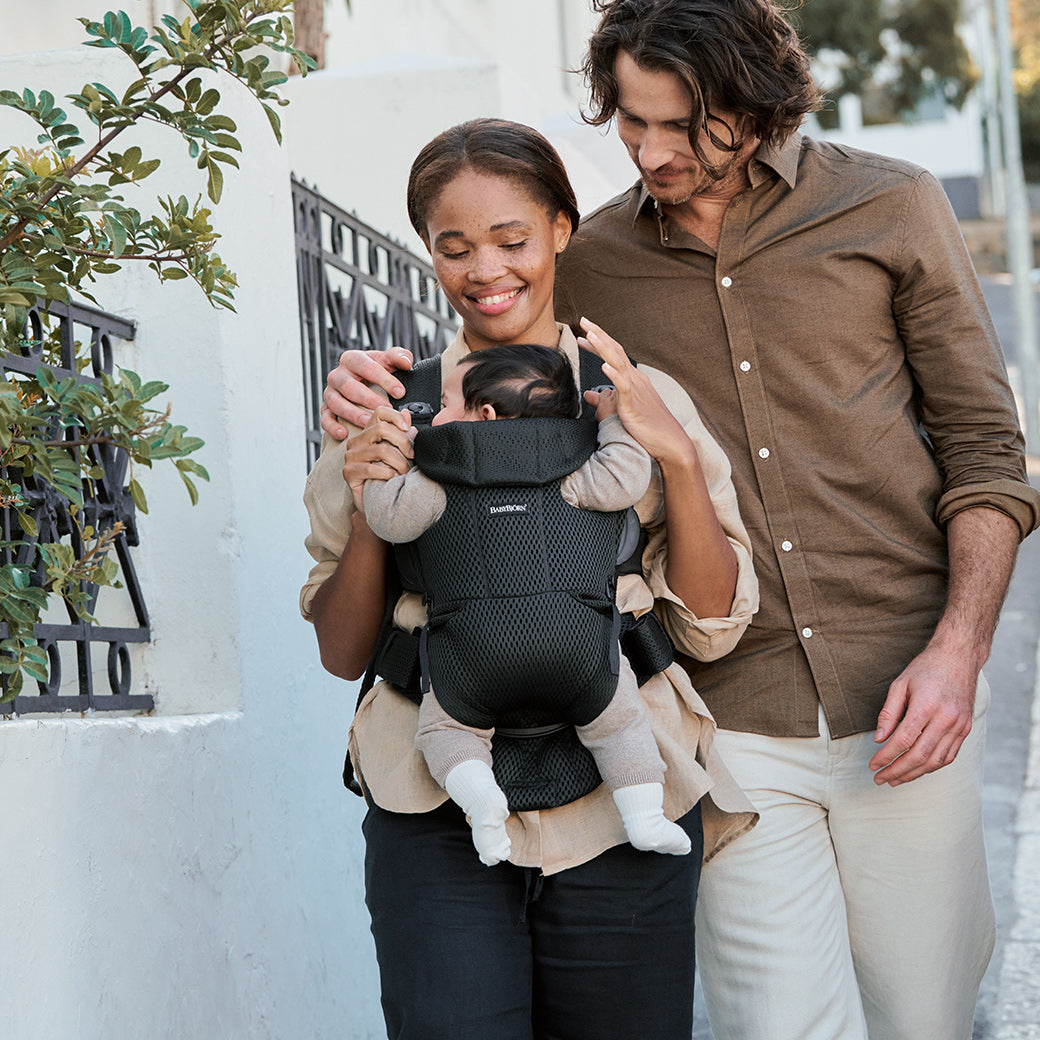 Mom and dad walking with baby in Babybjorn Baby Carrier Free in -- Color_Black 3D Mesh