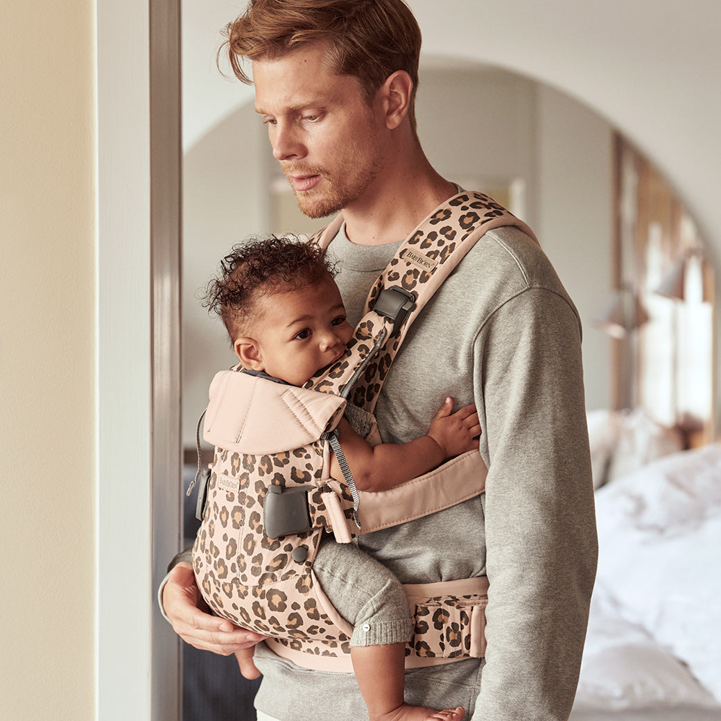 Dad in doorway with baby in Babybjorn Baby Carrier One in -- Color_Beige Leopard Cotton
