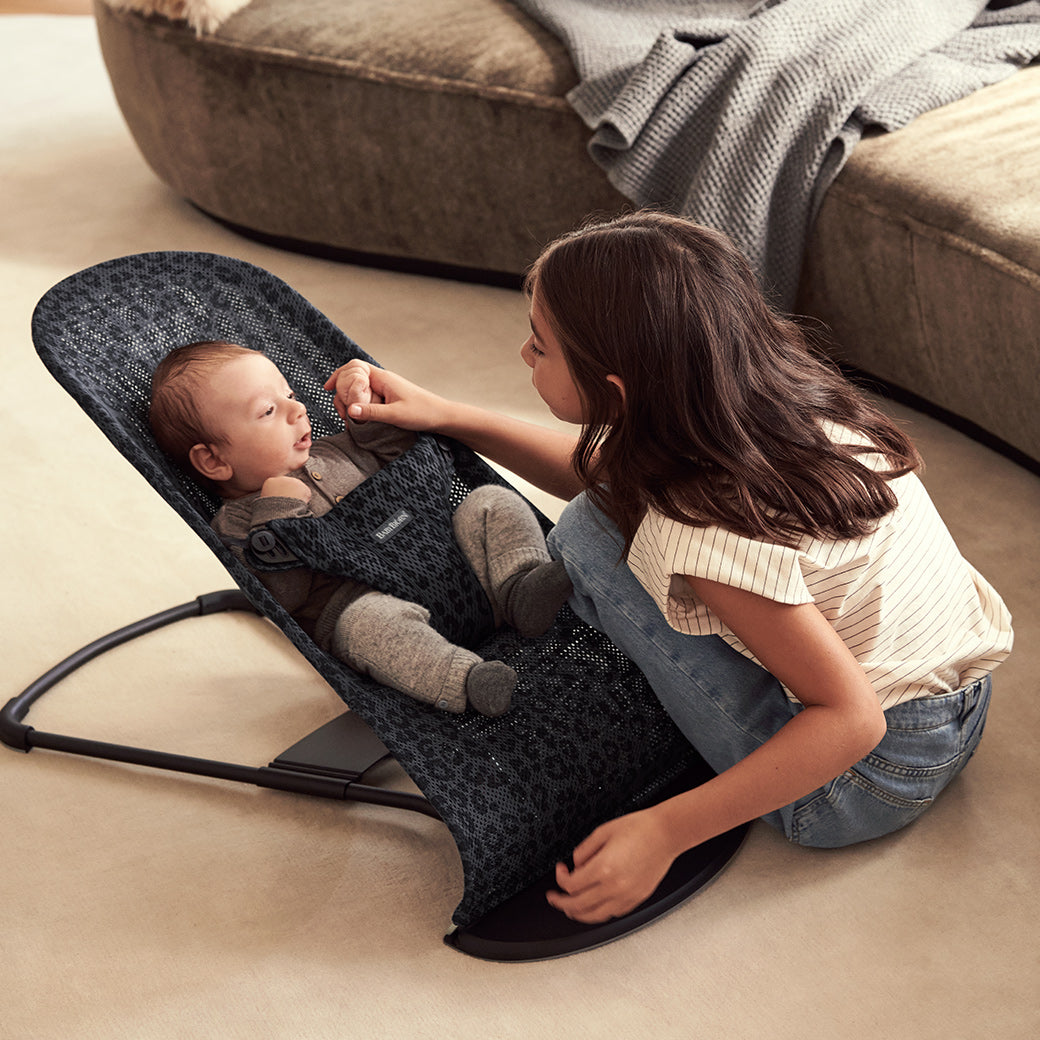 Child playing with baby in BABYBJÖRN Bouncer Bliss in -- Color_Anthracite Leopard Mesh