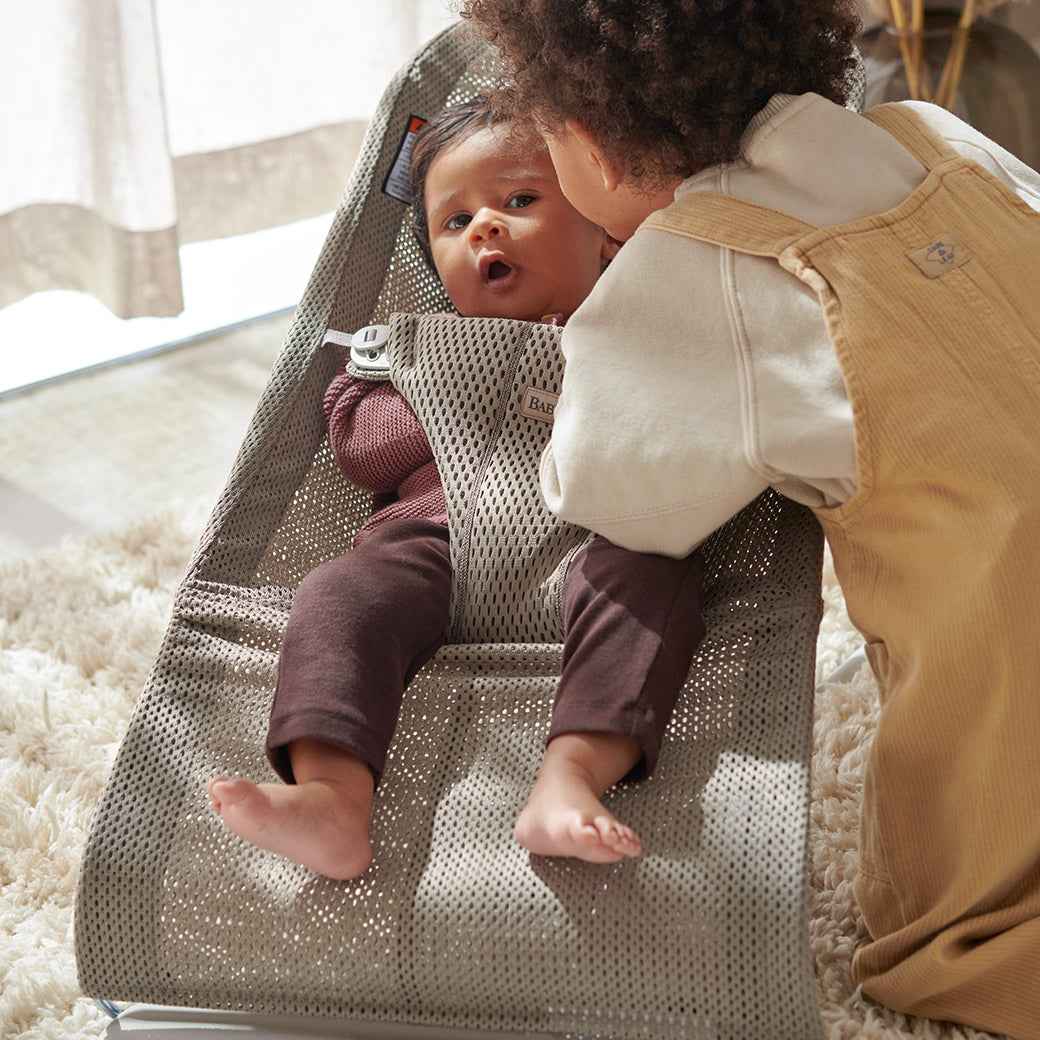 Toddler kissing baby in BABYBJÖRN Bouncer Bliss in -- Color_Beige Grey Mesh