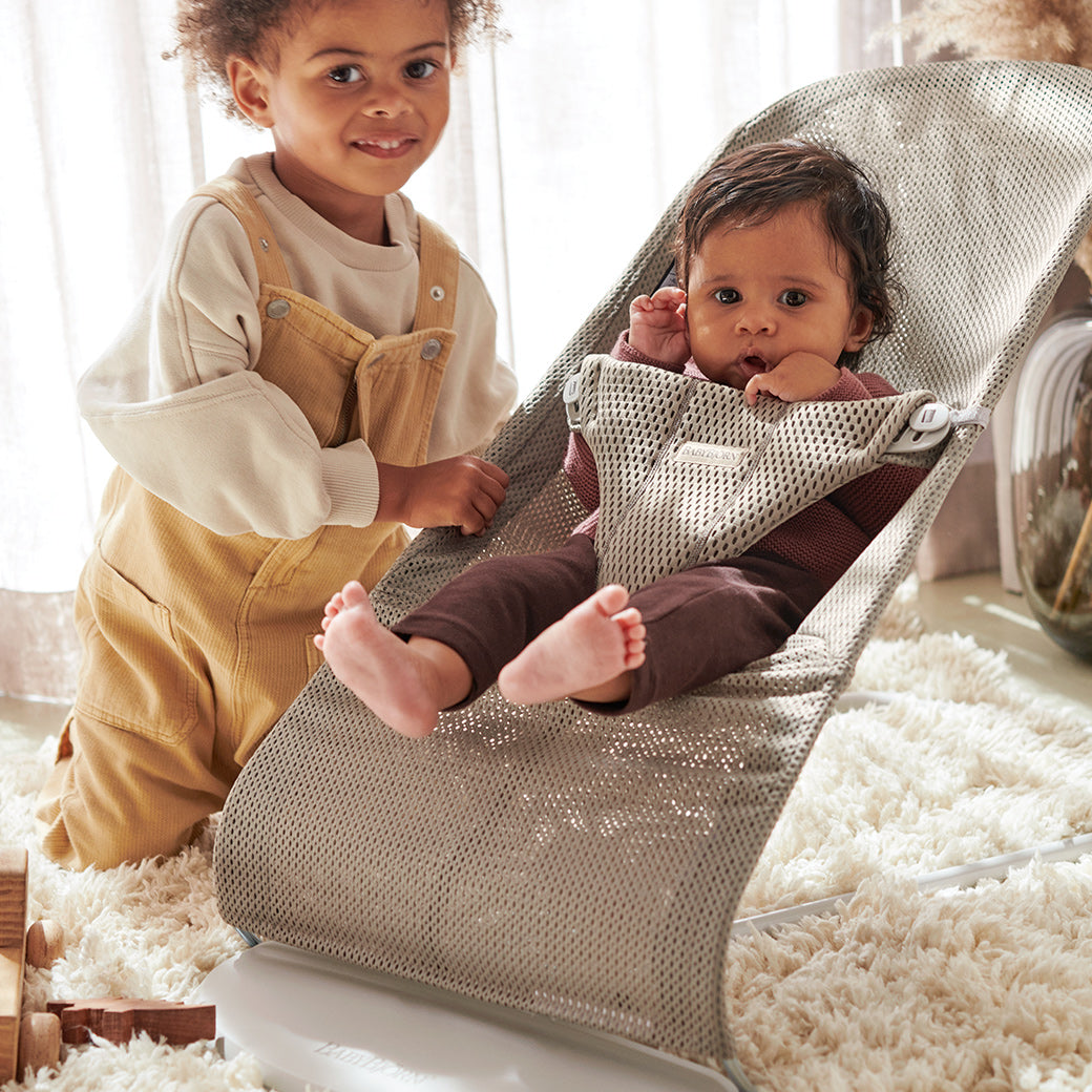 Toddler next to baby in BABYBJÖRN Bouncer Bliss in -- Color_Beige Grey Mesh