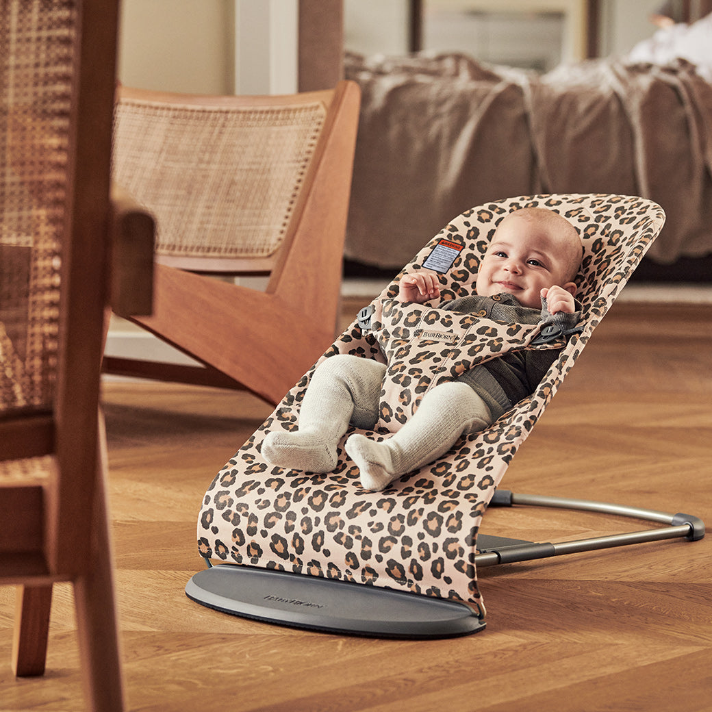 Baby smiling in BABYBJÖRN Bouncer Bliss in -- Color_Beige Leopard Classic Quilt Cotton
