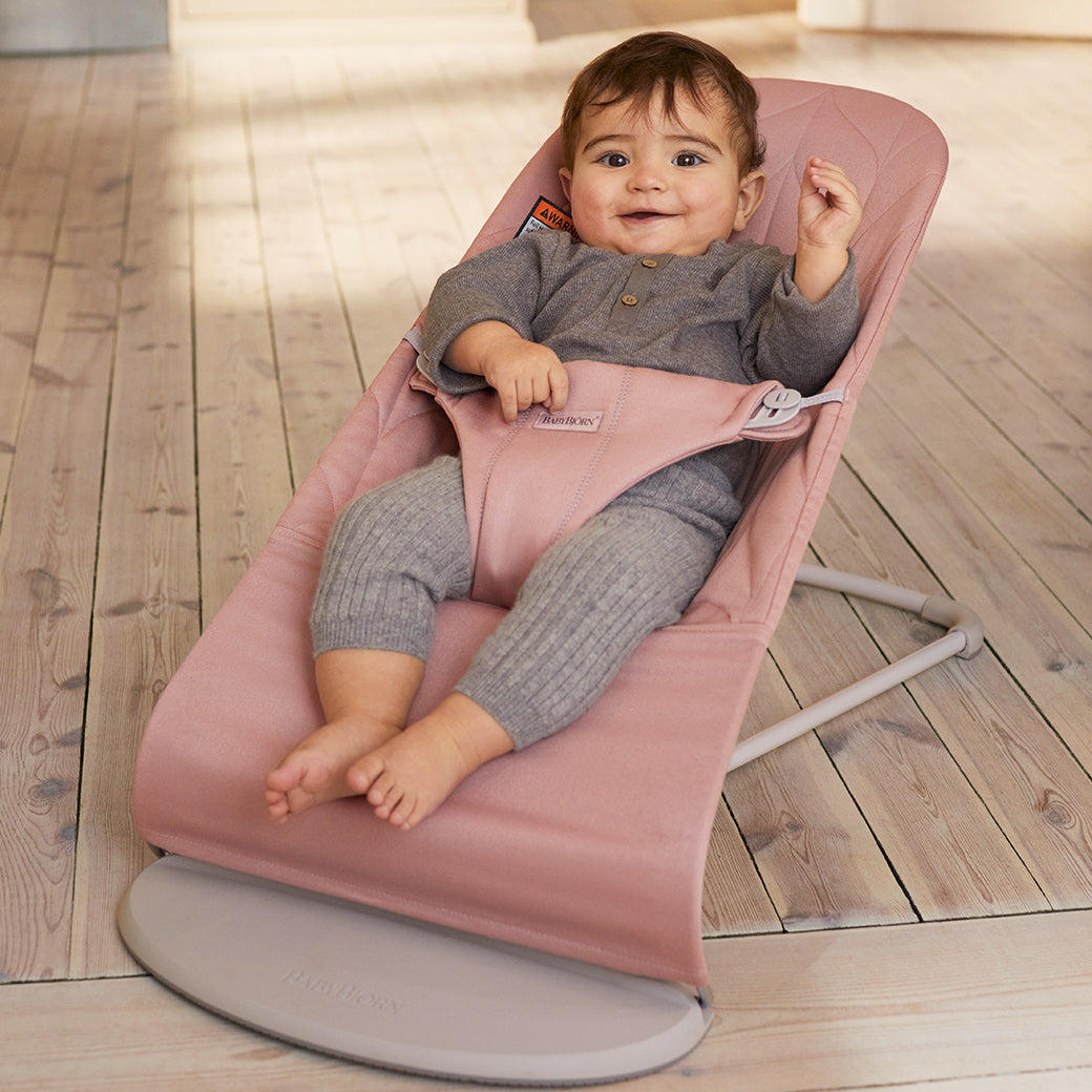 Happy baby sitting in BABYBJÖRN Bouncer Bliss in -- Color_Dusty Pink Woven, Petal Quilt