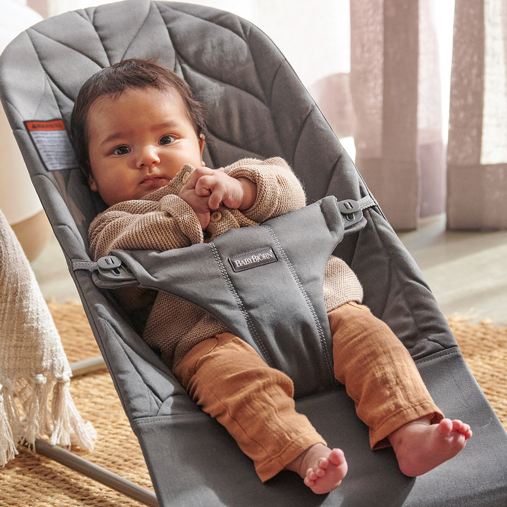 Baby calmly sitting in BABYBJÖRN Bouncer Bliss in -- Color_Light Grey Woven, Petal Quilt