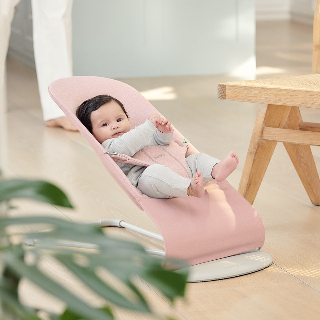 Baby in BABYBJÖRN Bouncer Bliss next to chair in -- Color_Light Pink 3D Jersey