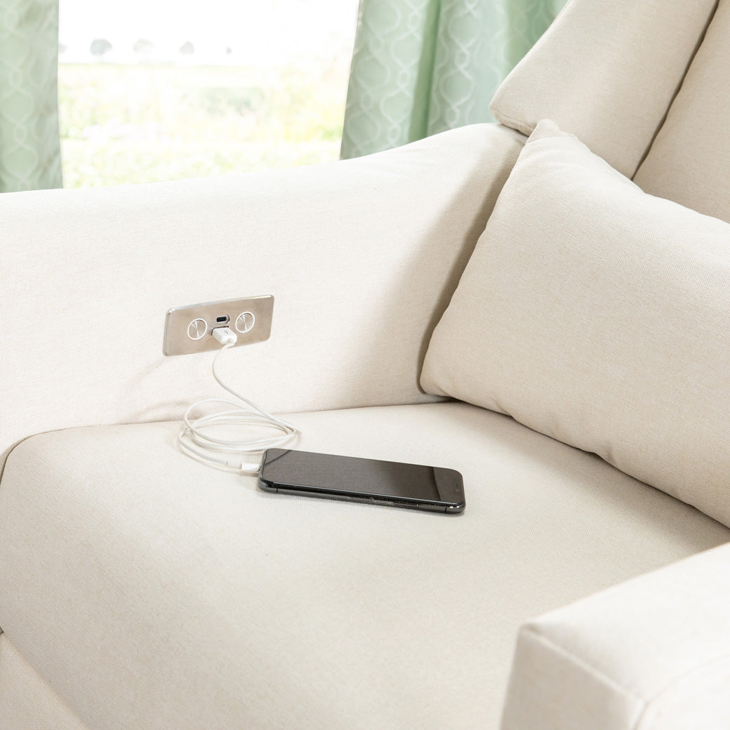 A phone charging on the Babyletto Kiwi Glider Recliner in -- Color_Performance Cream Eco-Weave