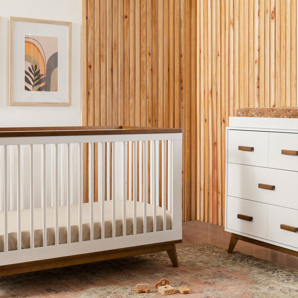 Babyletto's Scoot 3-in-1 Convertible Crib next to dresser  in -- Color_White/Natural Walnut