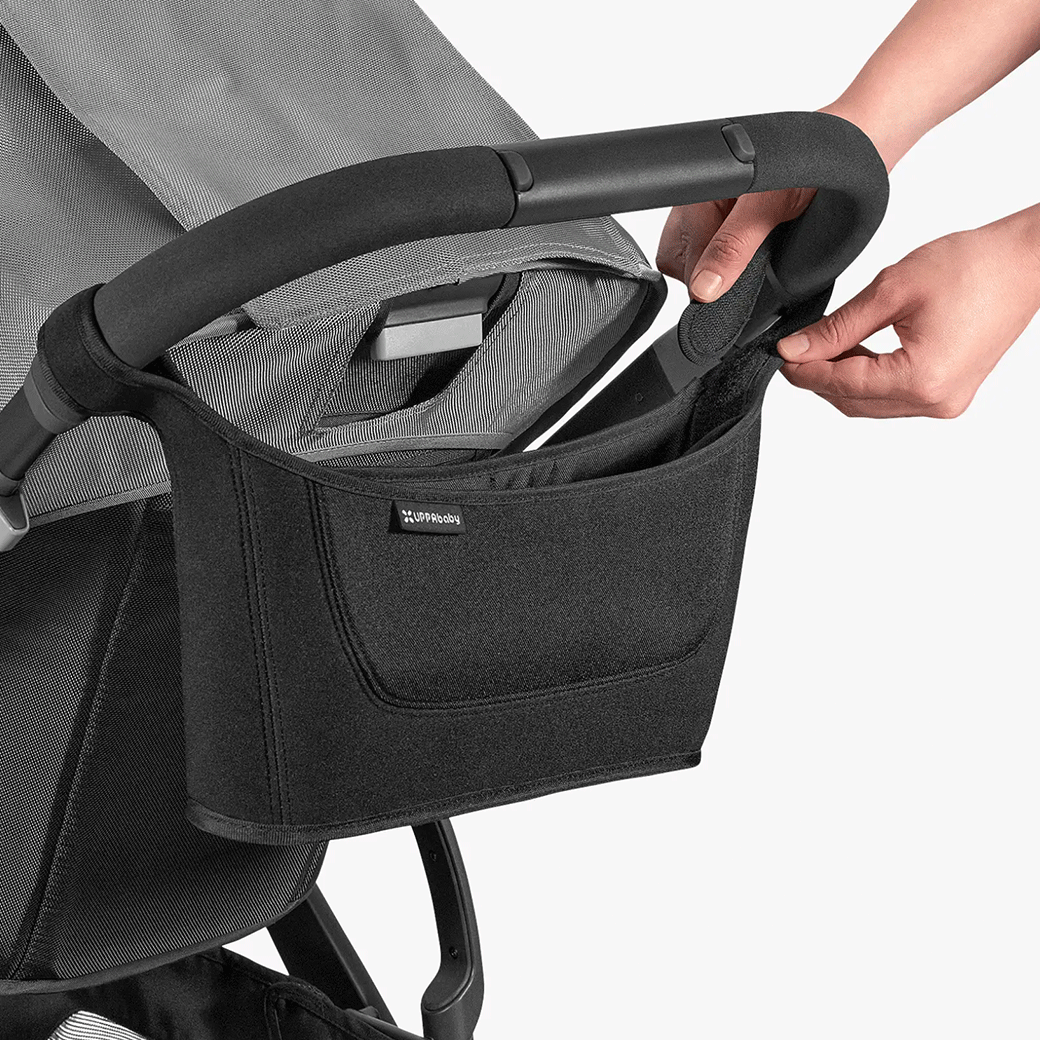 A person putting the UPPAbaby Carry-All Parent Organizer on a stroller 