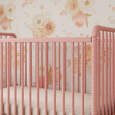 Lifestyle closeup view of the rails of the DaVinci’s Jenny Lind Crib in a floral room in -- Color_Blush Pink