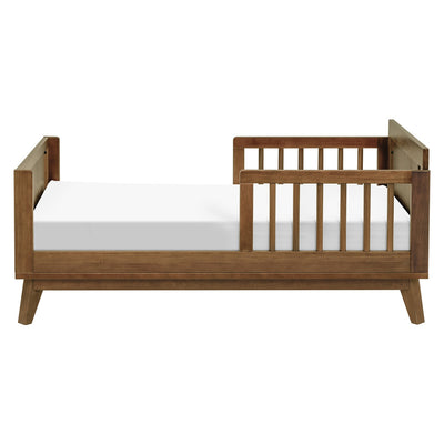 Side view of assembled Junior Bed Conversion Kit For Hudson And Scoot Crib with a mattress  in -- Color_Natural Walnut