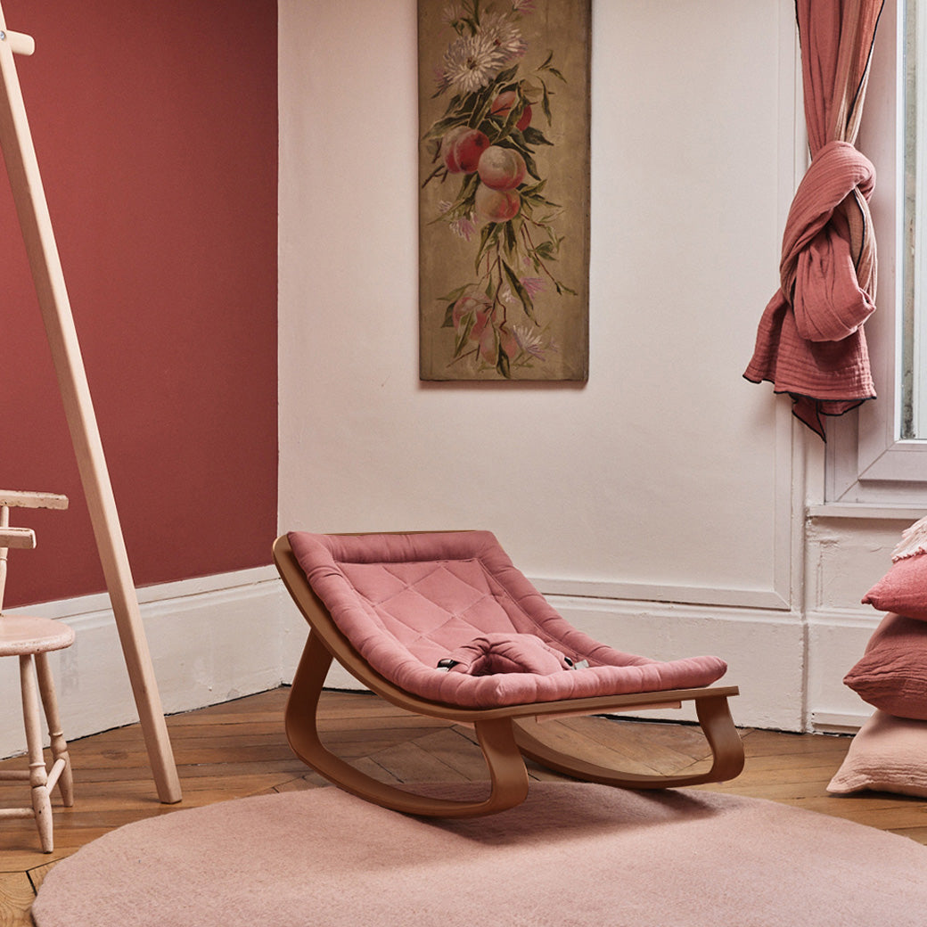 Charlie Crane LEVO Baby Rocker in a rose colored room under a painting in  -- Color_Bois de Rose _ Walnut