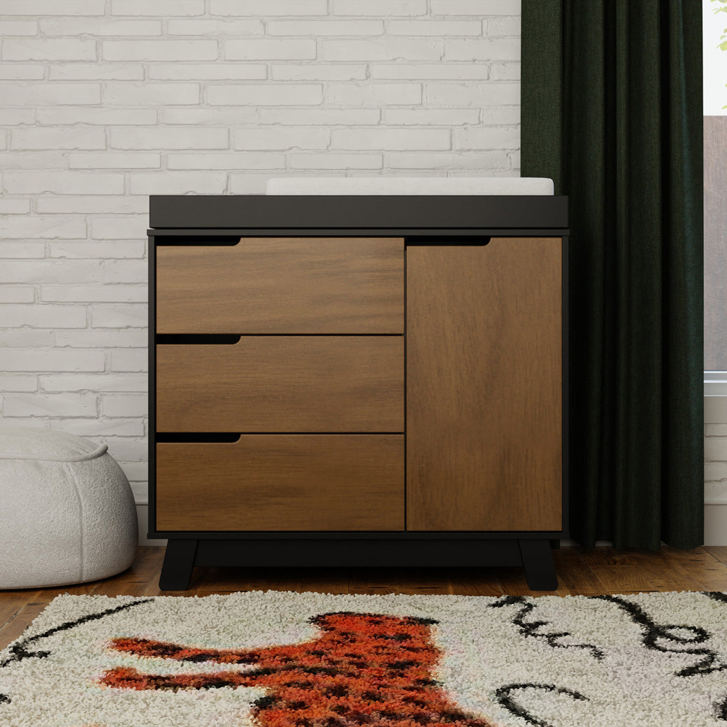 Lifestyle front view of The Babyletto Hudson Changer Dresser next to window in -- Color_Black/Natural Walnut